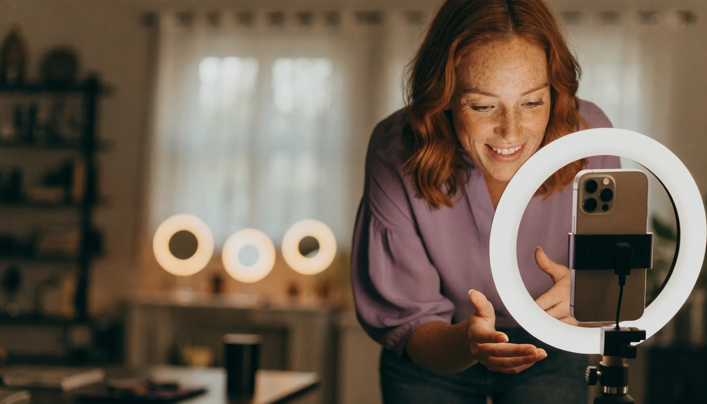 Eine selbstständige Video-Bloggerin nimmt mit Smartphone und Ringlicht einen Beitrag für ihren Kanal auf.